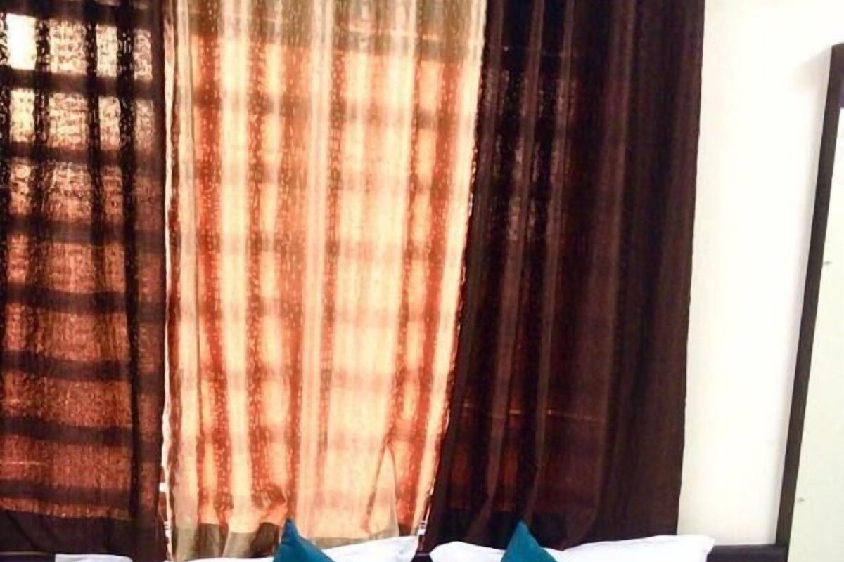 A bed with white linens, two teal pillows, and a blue floral bedspread.