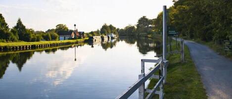 A calm canal with a wooden fence and a pathway alongside.