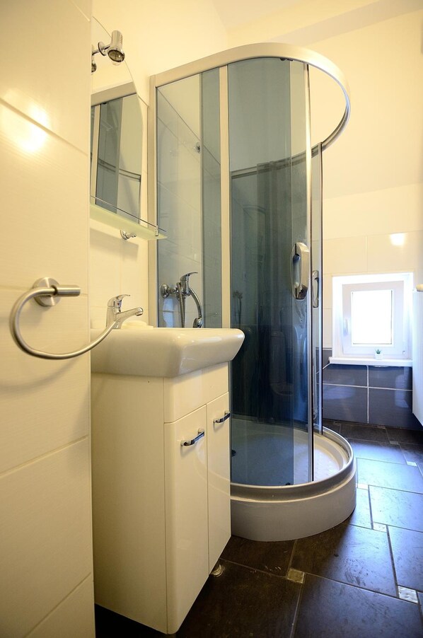 A modern bathroom with a glass-enclosed shower, a white sink, and a mirror above it. - Victus Apartamenty - Adams (Sopot)