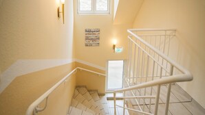 A stairwell with white railings, a handrail, and a small window at the top. - Achilleon III (Geesthacht)