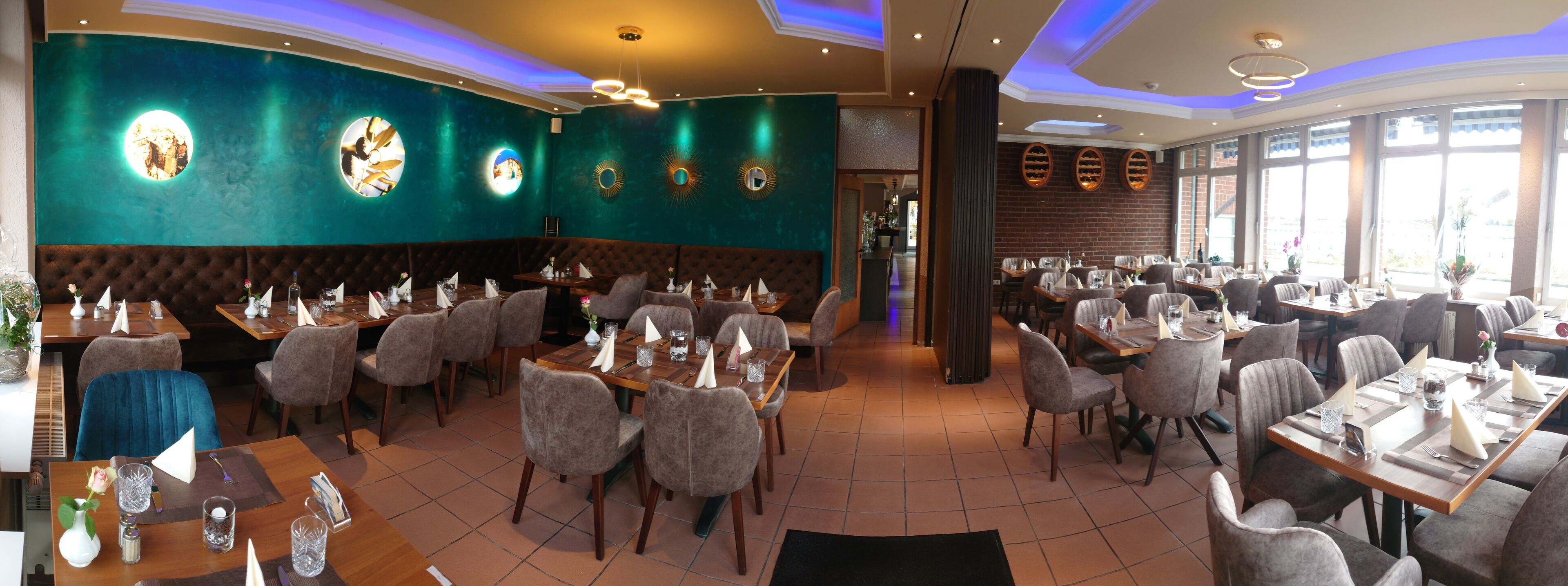 A restaurant with multiple dining areas, each with tables and chairs. There are decorative wall panels and a large window providing natural light.