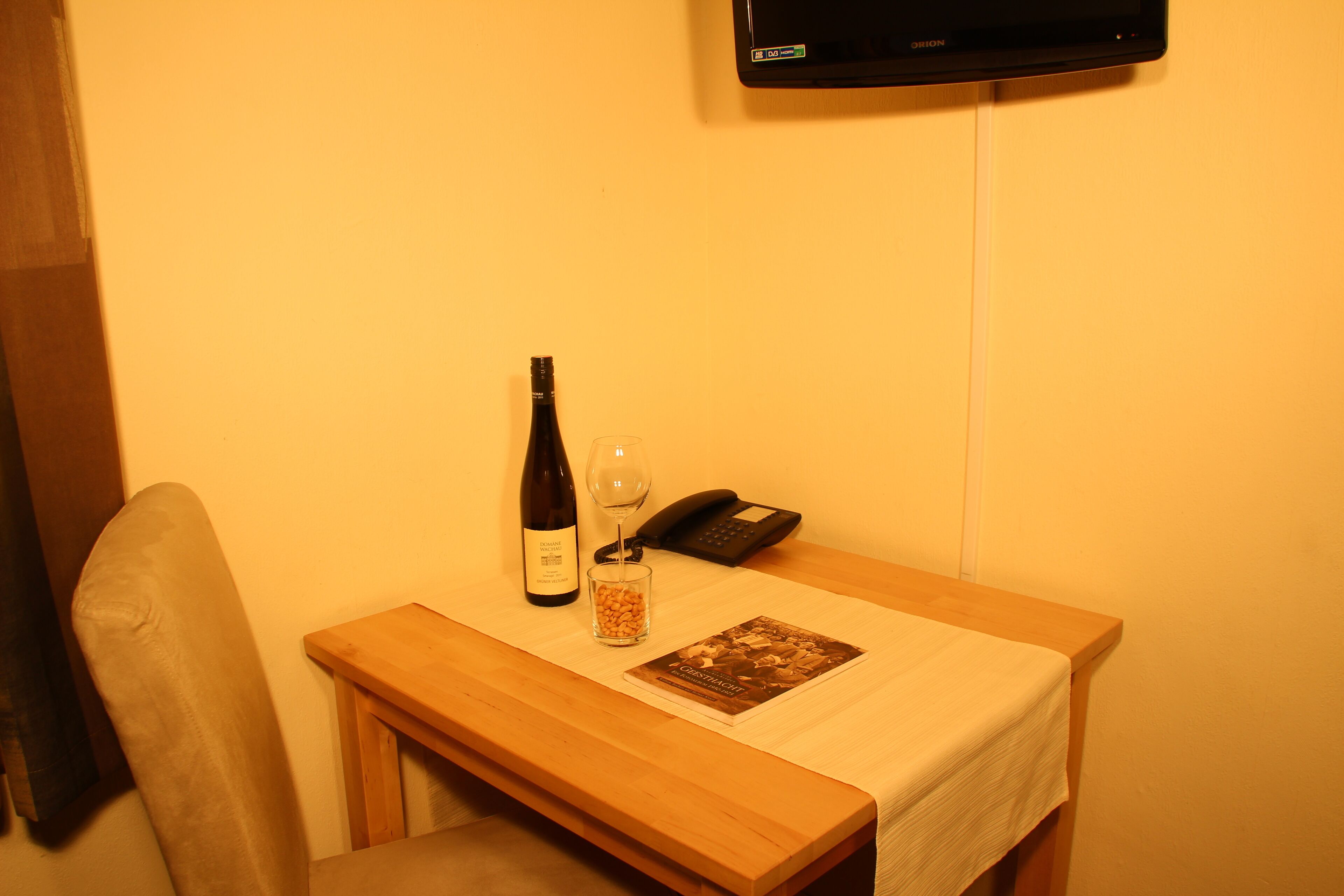 A small wooden table with a wine bottle, a glass, and a phone.