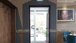 A hotel lobby with a reception desk, seating area, and an exit sign. - Achilleon III (Geesthacht)