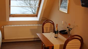 Un comedor con una mesa, sillas, un ventanal con vistas, un radiador y un televisor montado en la pared.