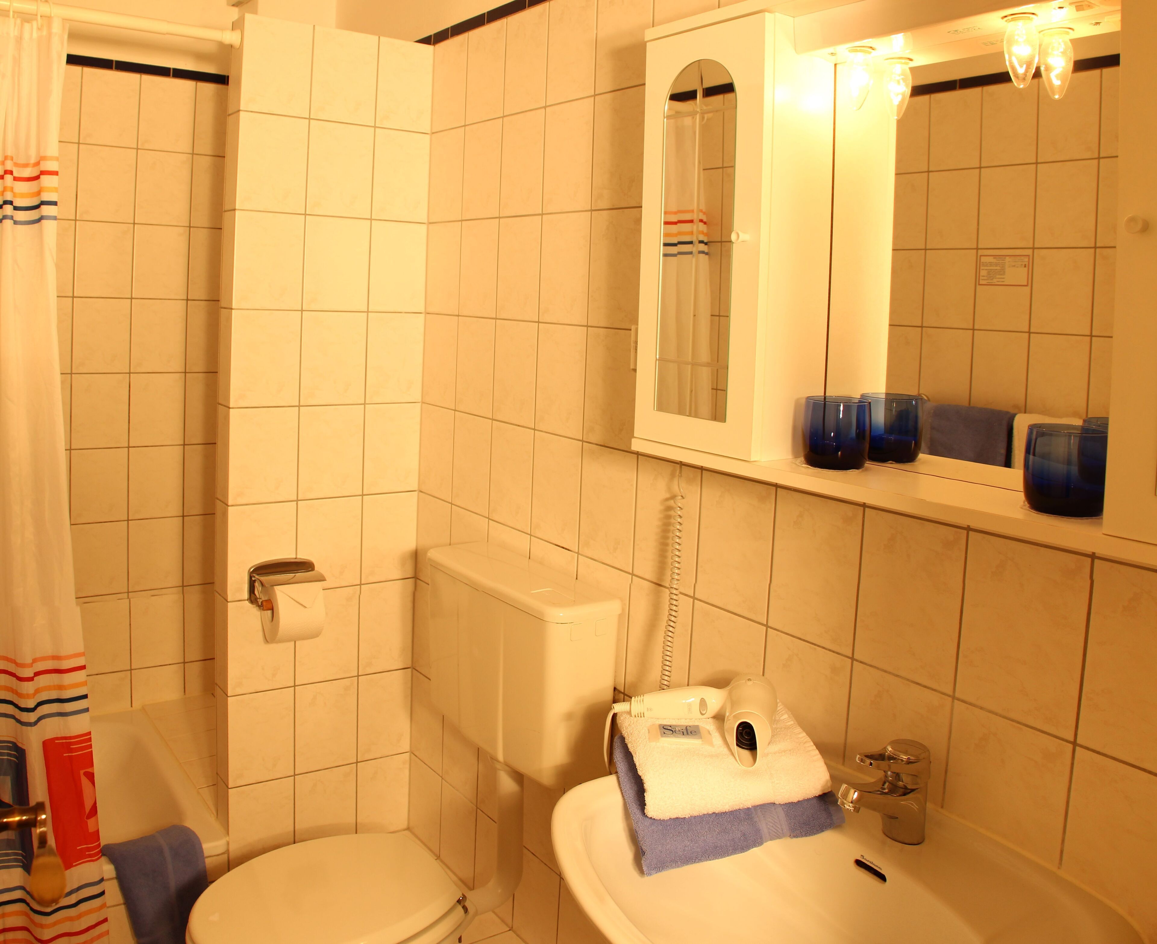 Et badeværelse med toilet, håndvask og et spejl over vasken.