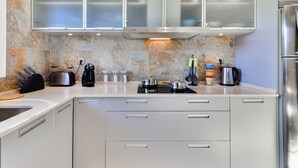 A modern kitchen with white cabinets, a built-in oven, a coffee maker, and a kettle. - Falesia Beach B (Albufeira)