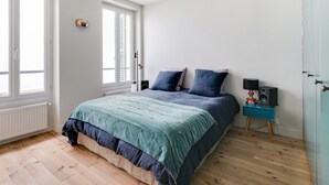 A bedroom with a bed, a nightstand, a lamp, and a window. - Sumptuous house with patio (Paris)