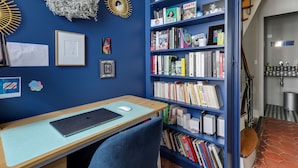 A room with a blue bookshelf filled with books, a desk with a laptop, and a chair. There are framed pictures and a wreath on the wall. - Sumptuous house with patio (Paris)