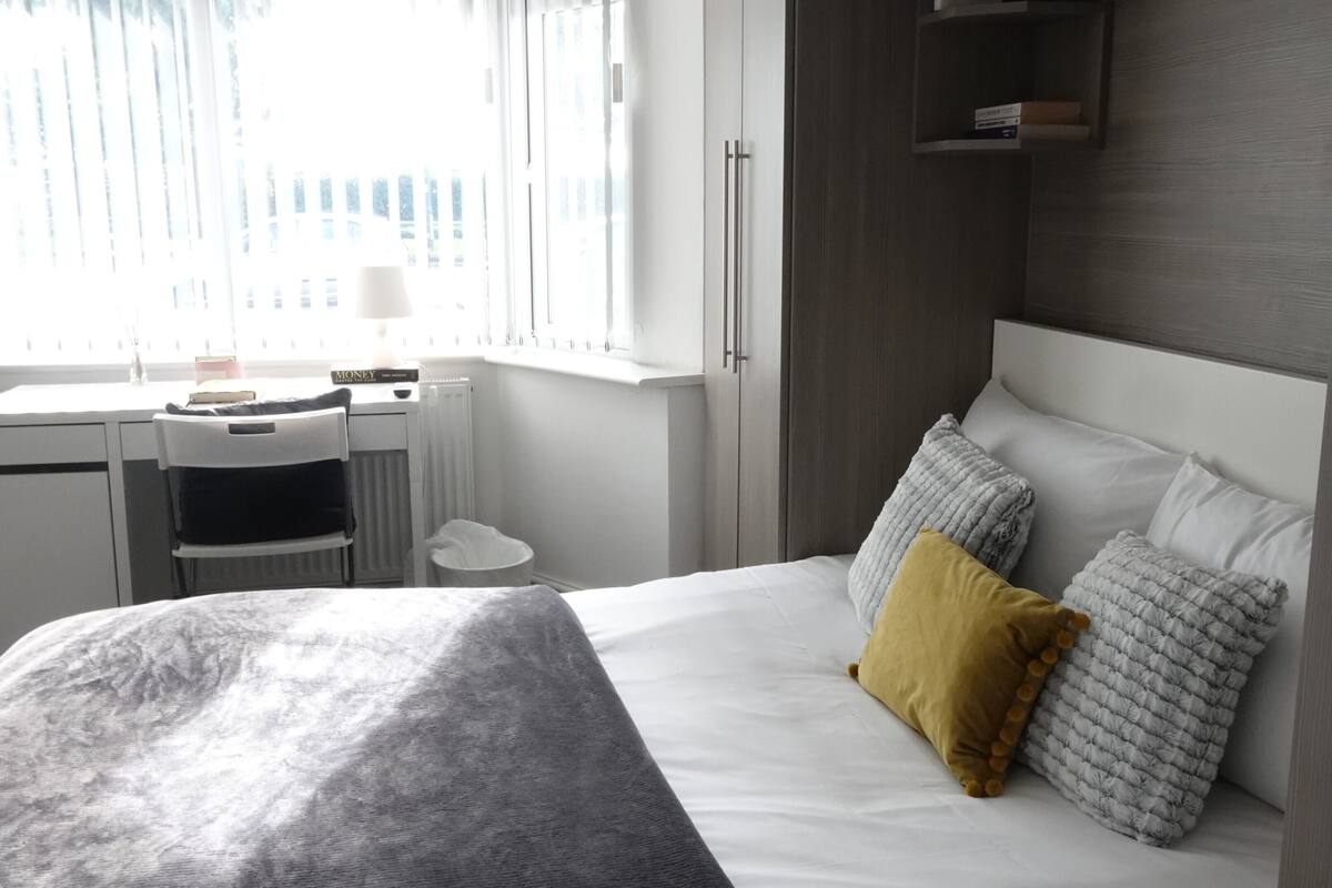 Ein modernes Hotelzimmer mit Bett, Nachttisch und Schreibtisch mit Stuhl.
