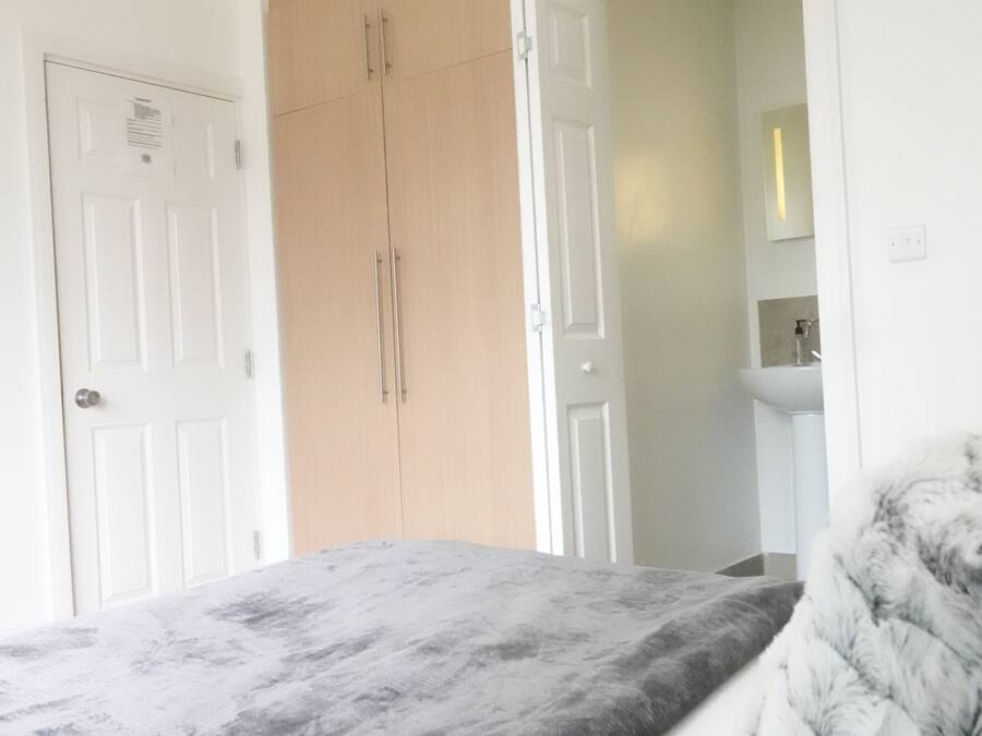 Un dormitorio con cama, armario y baño visible a través de una puerta abierta.
