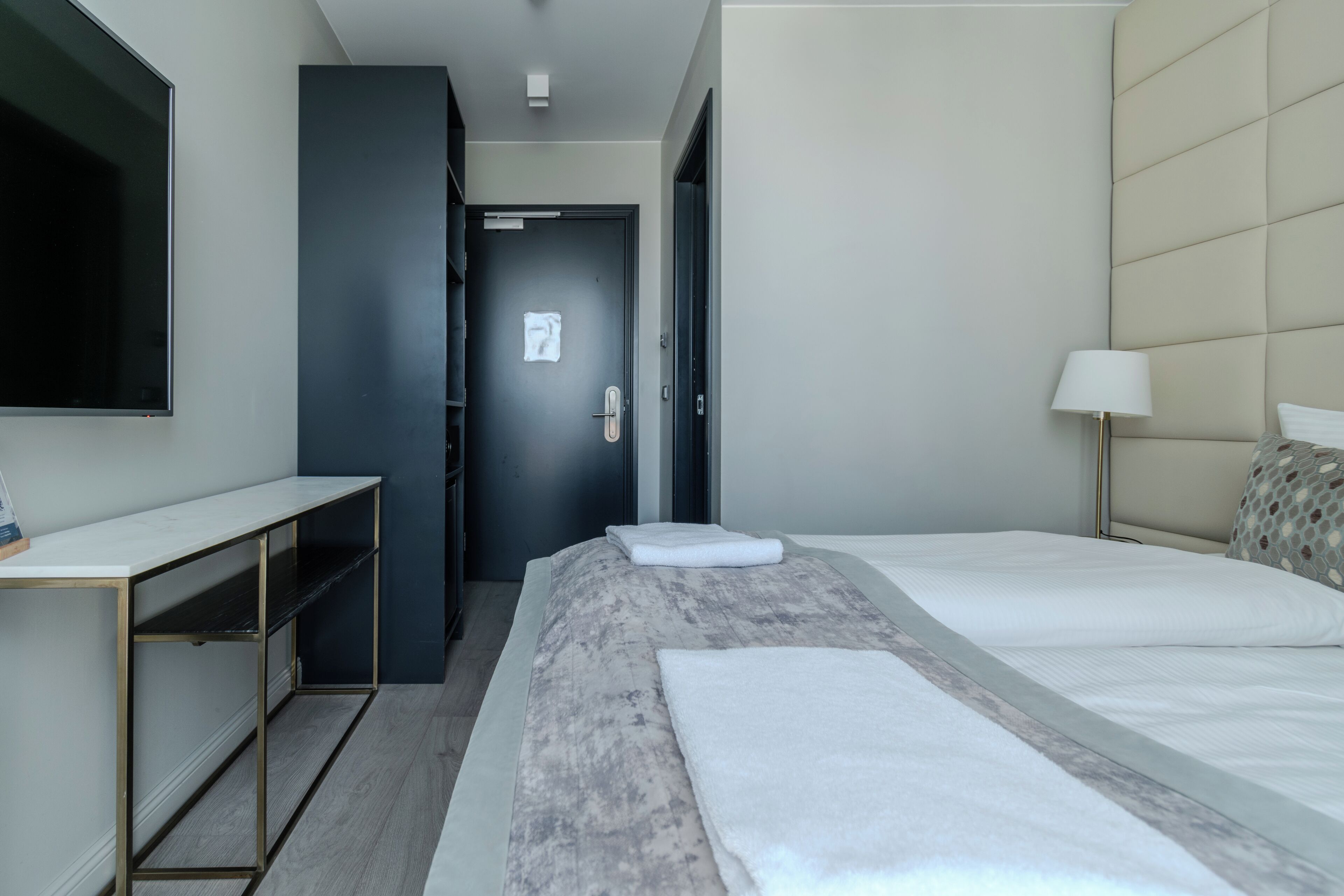 Una habitación de hotel con cama, escritorio, armario y televisión.