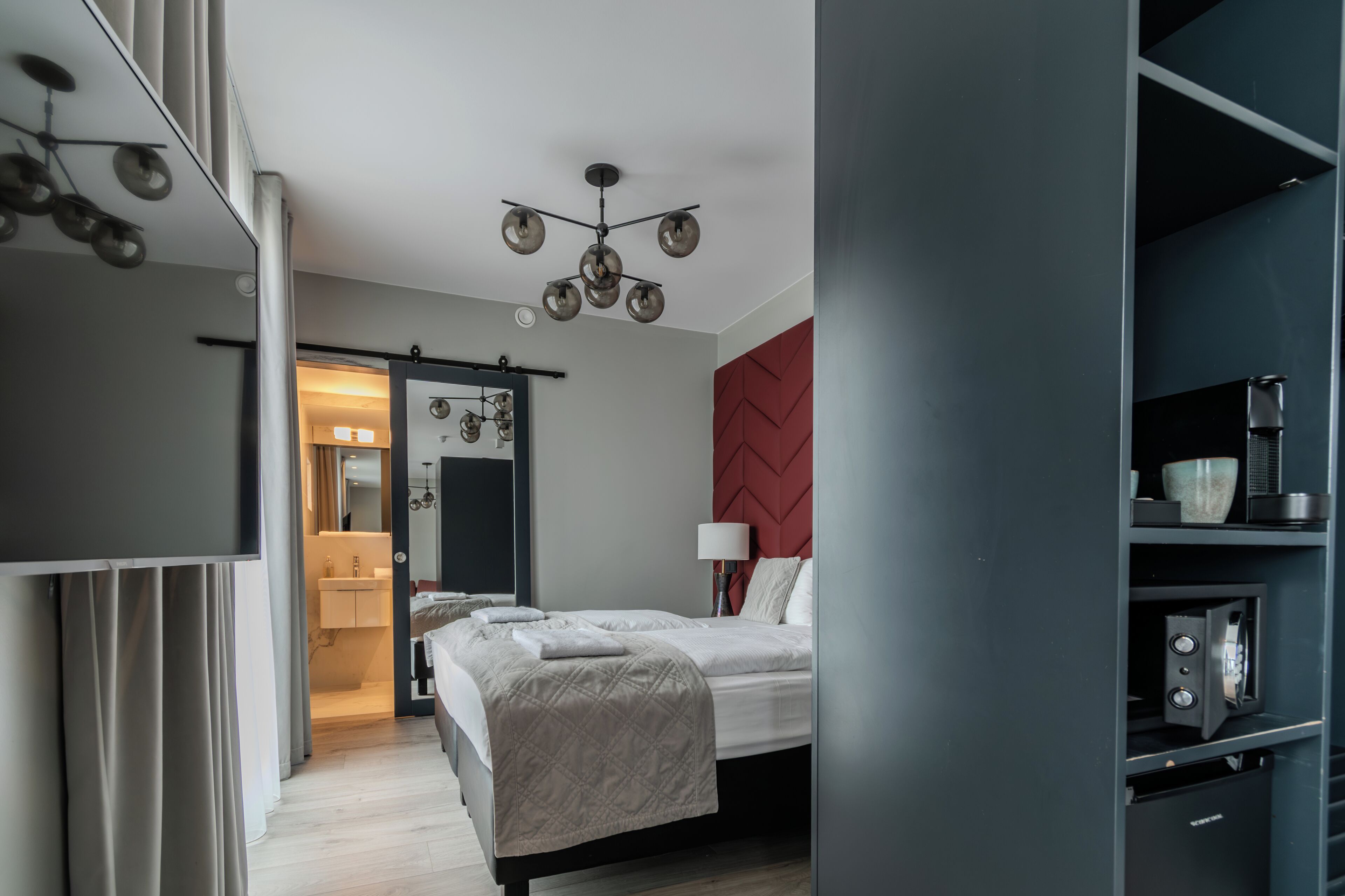 Un dormitorio moderno con cama, mesita de noche y una pared de acento roja.