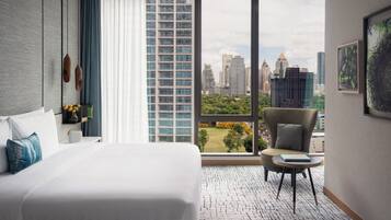 Una camera d'albergo con un letto grande, una sedia, un tavolino e vista sulla città.