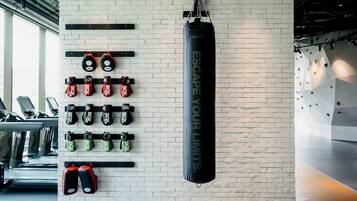 A gym with various exercise equipment, including punching bags and weightlifting stations.