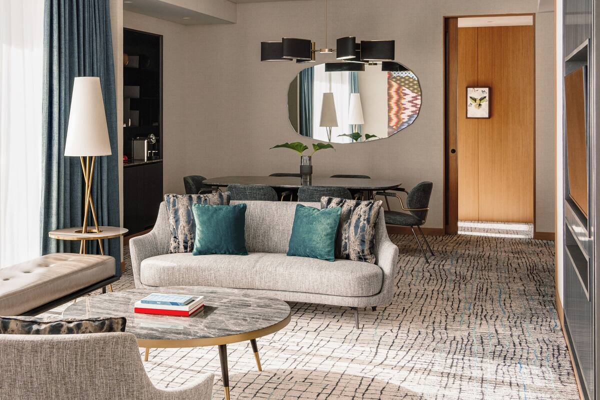 Ein modernes Hotelzimmer mit einer Couch, einem Couchtisch und einem Essbereich.