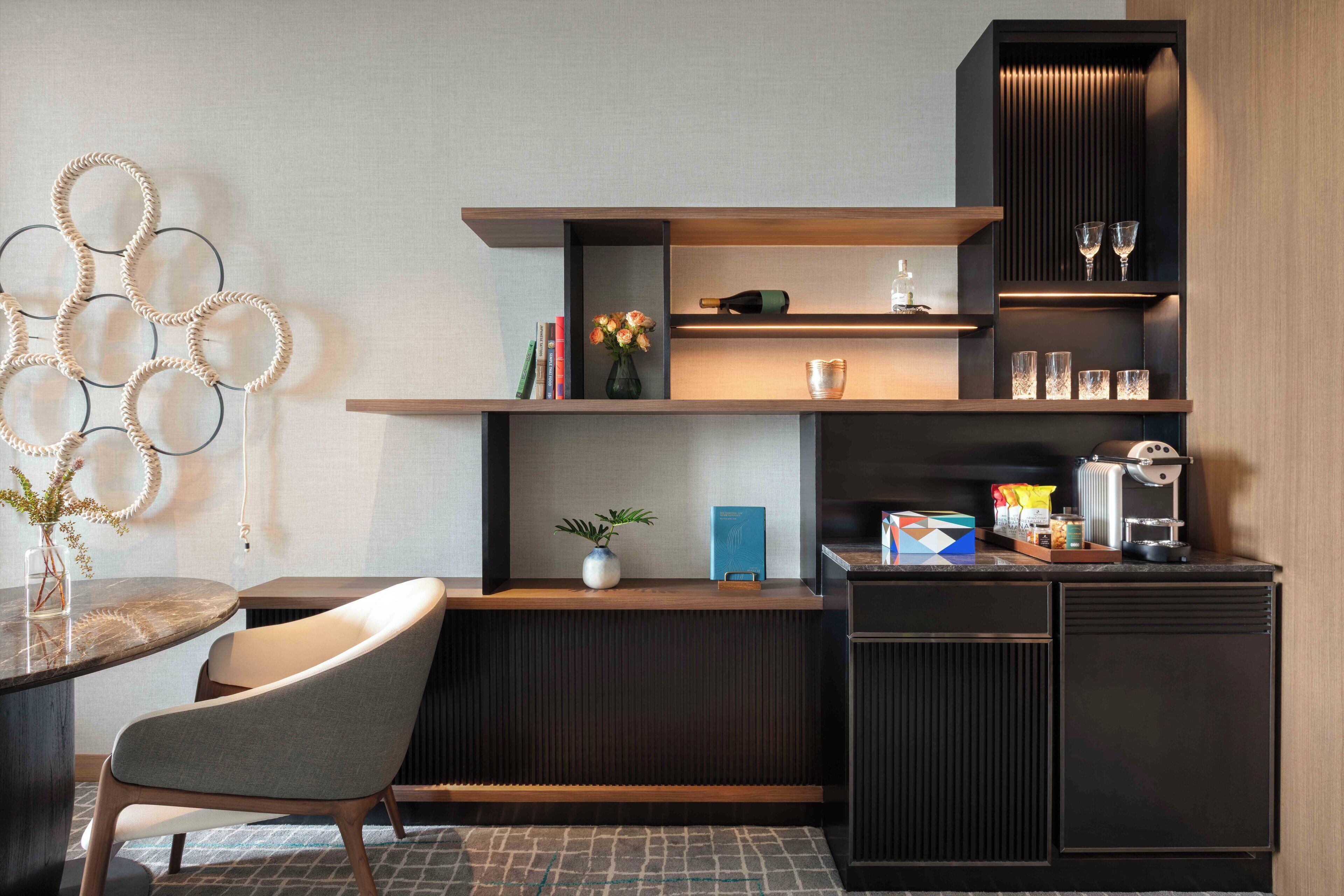 A modern kitchen with a built-in coffee machine, a vase with flowers, and a wine bottle on the countertop.