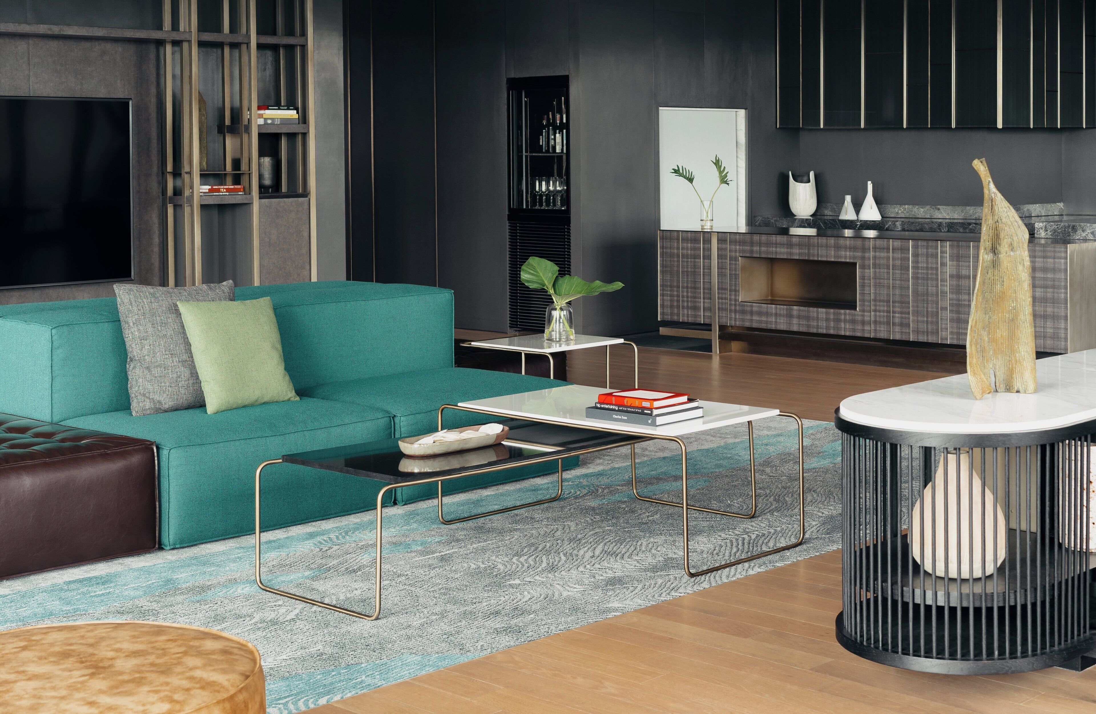 A modern living room with a teal sofa, a coffee table, a TV, a bookshelf, and a fireplace.
