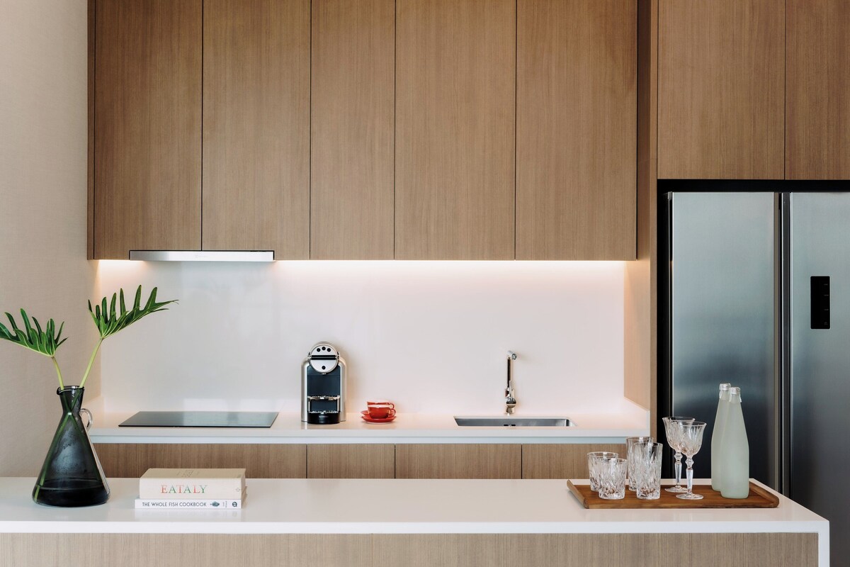 Une cuisine moderne avec des meubles en bois, un réfrigérateur en acier inoxydable, une machine à café et un livre intitulé « Le grand livre de recettes de poisson ».