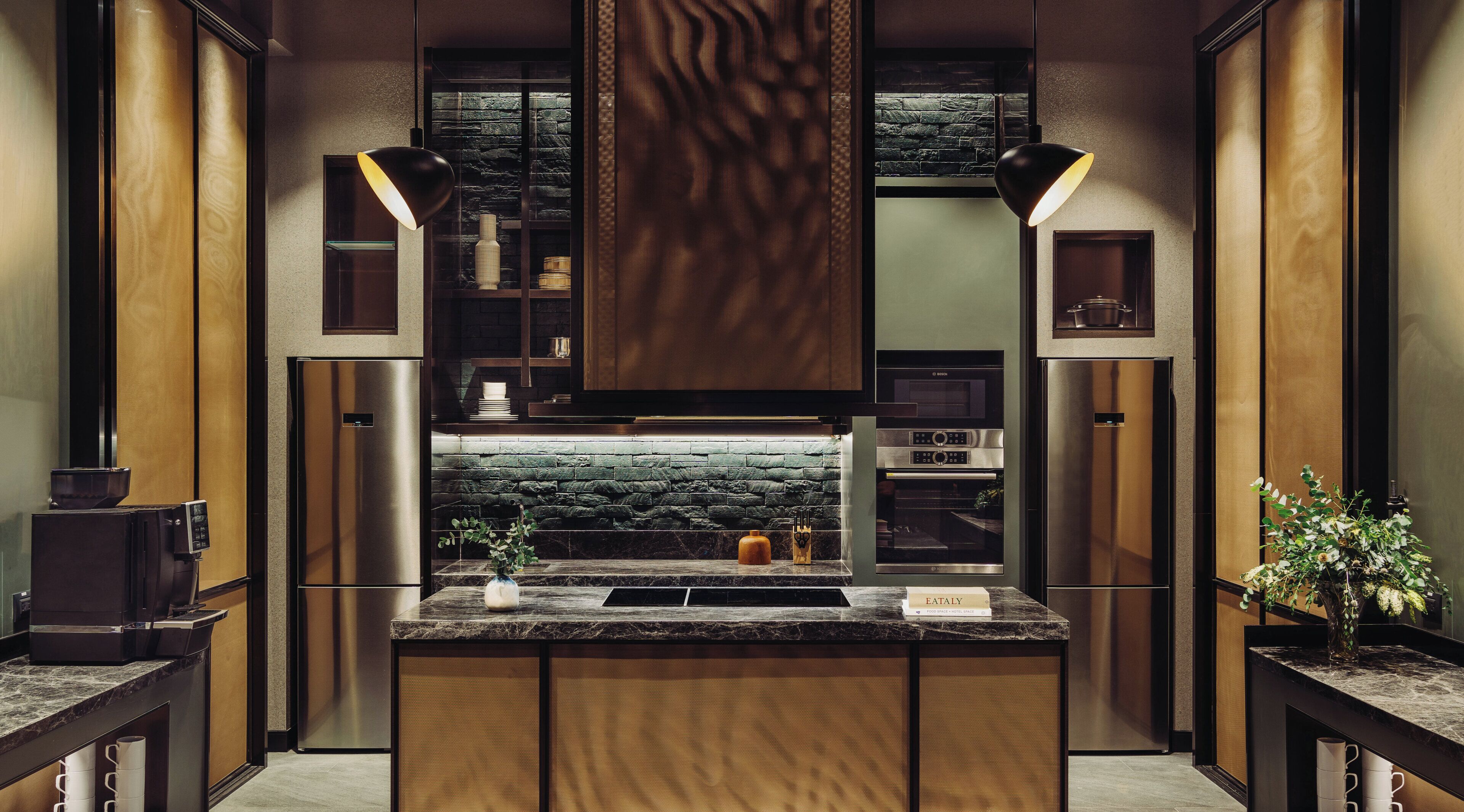 Una cocina moderna con una isla central, electrodomésticos integrados y un salpicadero de piedra.