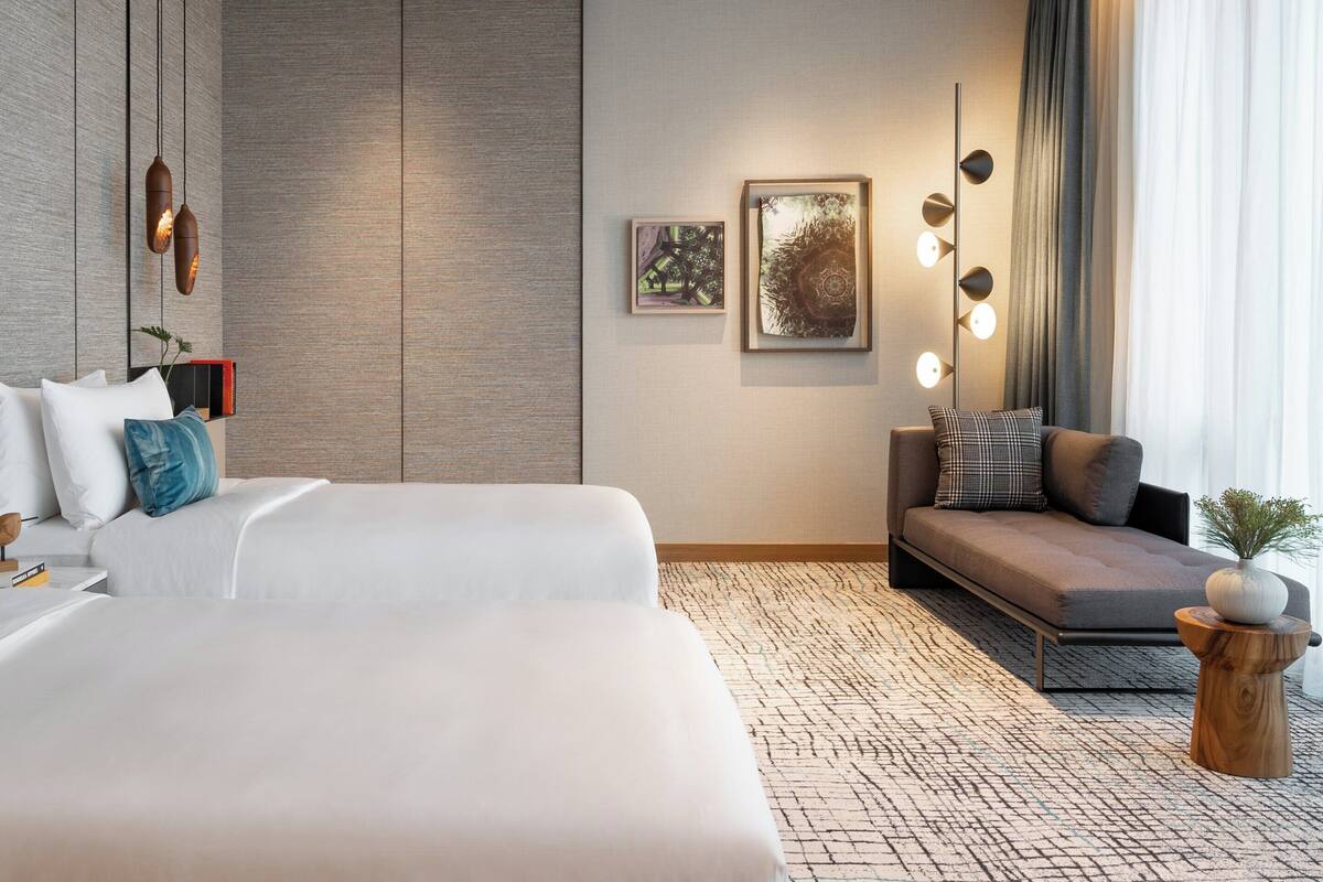 Ein modernes Hotelzimmer mit einem großen Bett, einer Couch und einem kleinen Tisch mit einer Vase.