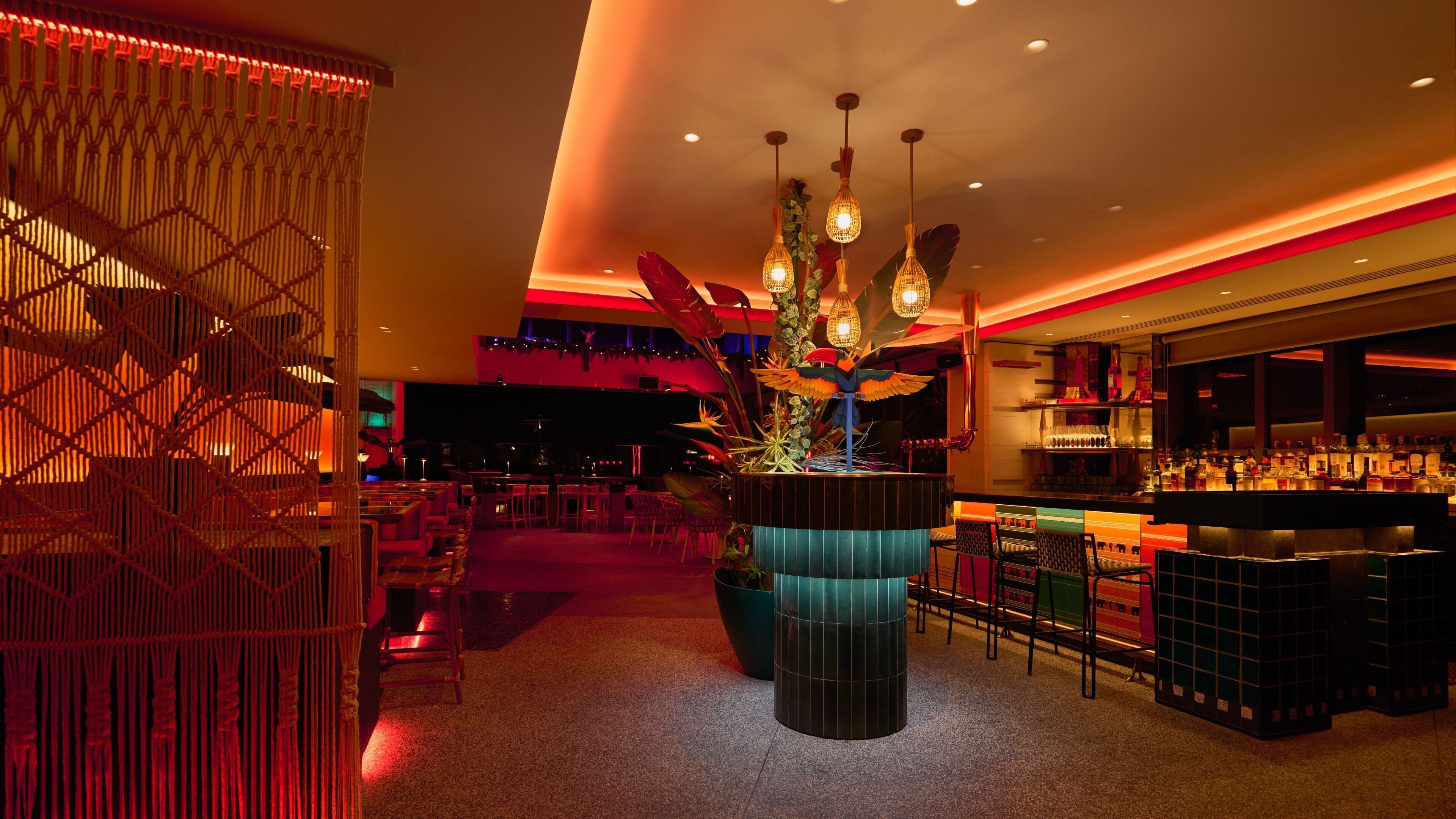 Zona de bar con asientos, una barra y iluminación decorativa.