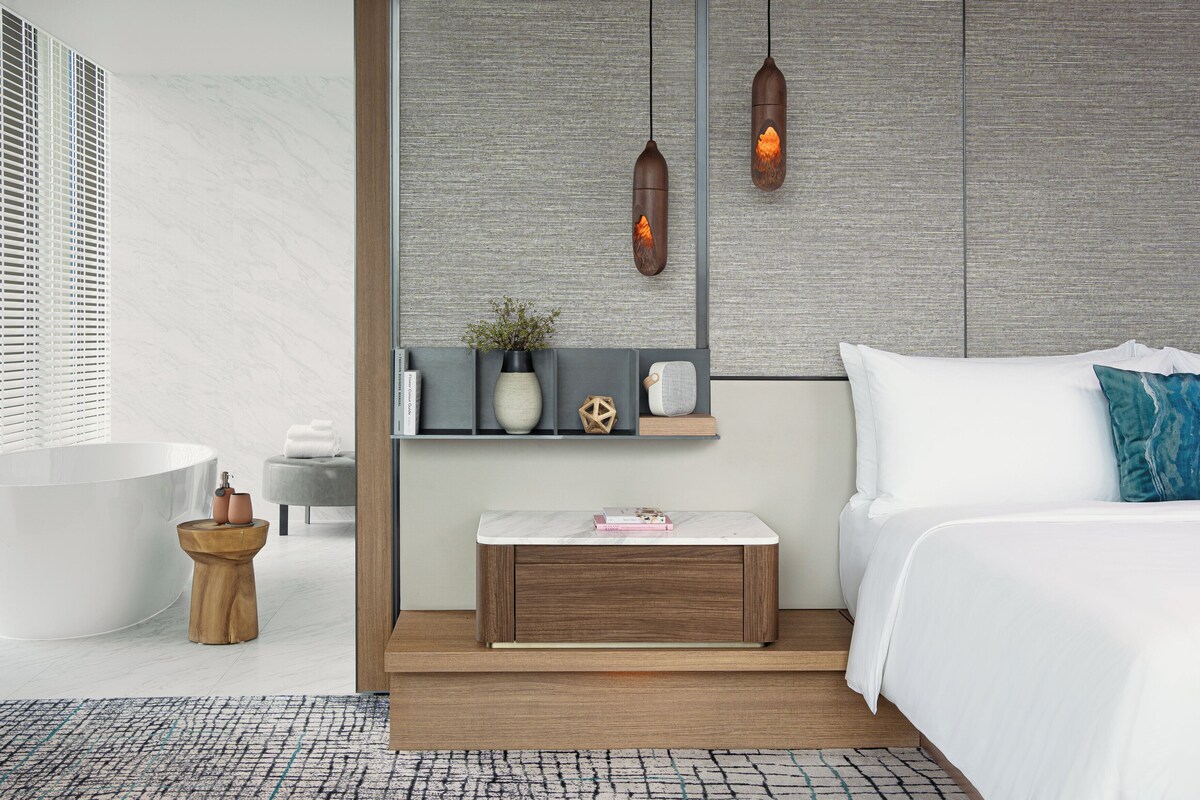 Une chambre à coucher moderne avec un lit, une table de chevet et une étagère murale agrémentée d’objets décoratifs.