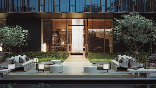 Un espace extérieur aménagé avec des meubles en osier et un chemin menant à l’entrée d’un bâtiment.