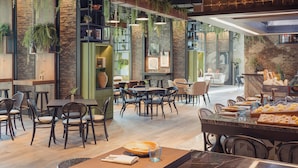 Un restaurant moderne avec des tables et des chaises en bois, des plantes suspendues et des murs en briques.
