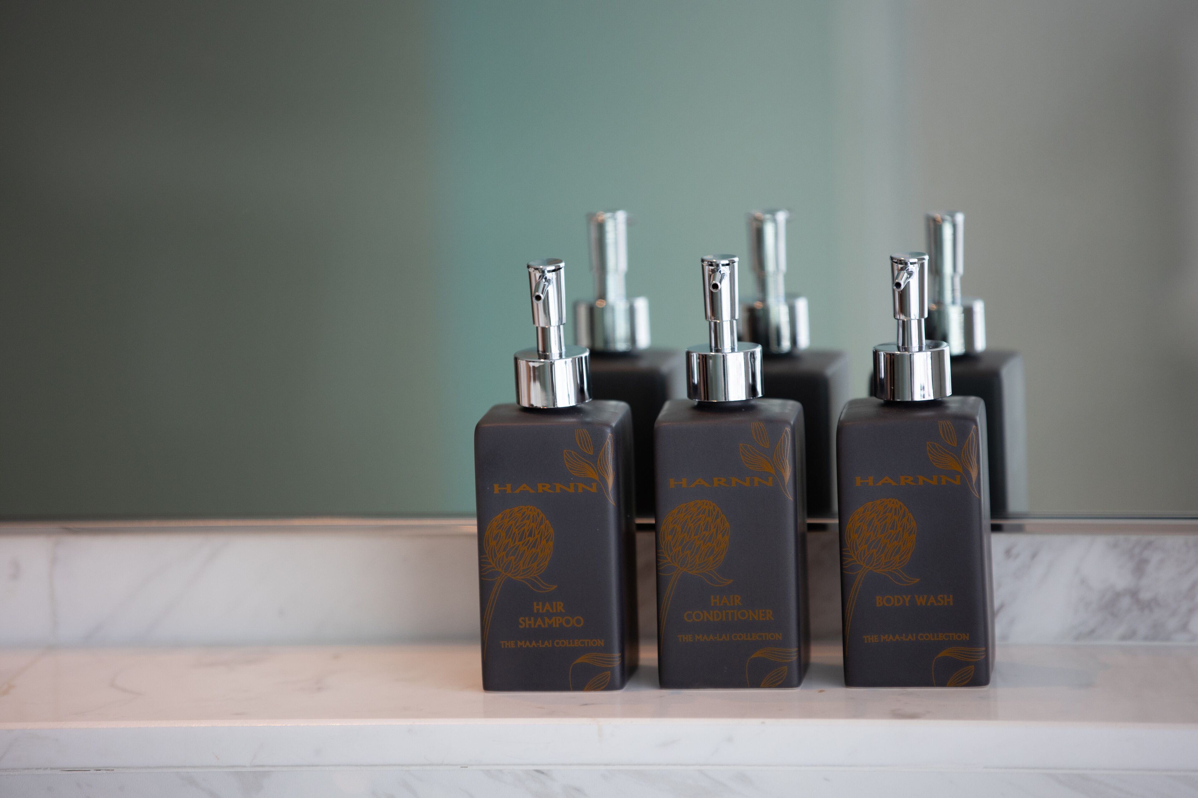 Trois flacons de produits capillaires de la marque Harnn, posés sur une surface en marbre.