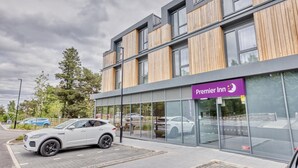 A modern hotel with a prominent 'Premier Inn' sign, large windows, and a car parked in front.