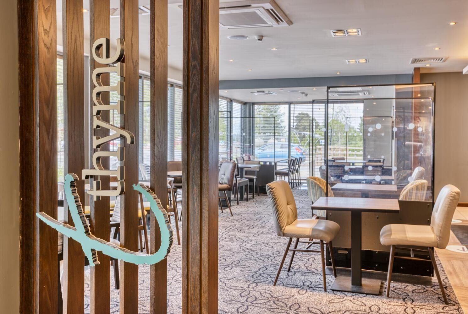 Un hall d’hôtel moderne avec un comptoir d’accueil, un espace salon et de grandes fenêtres.