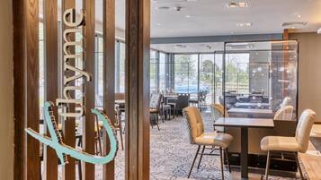Een moderne hotel lobby met een receptiebalie, een zithoek en grote ramen.