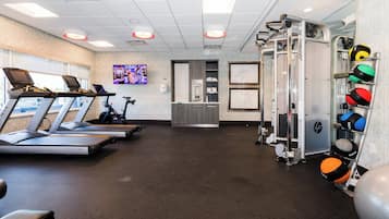 A gym with treadmills, a weight machine, and exercise balls.