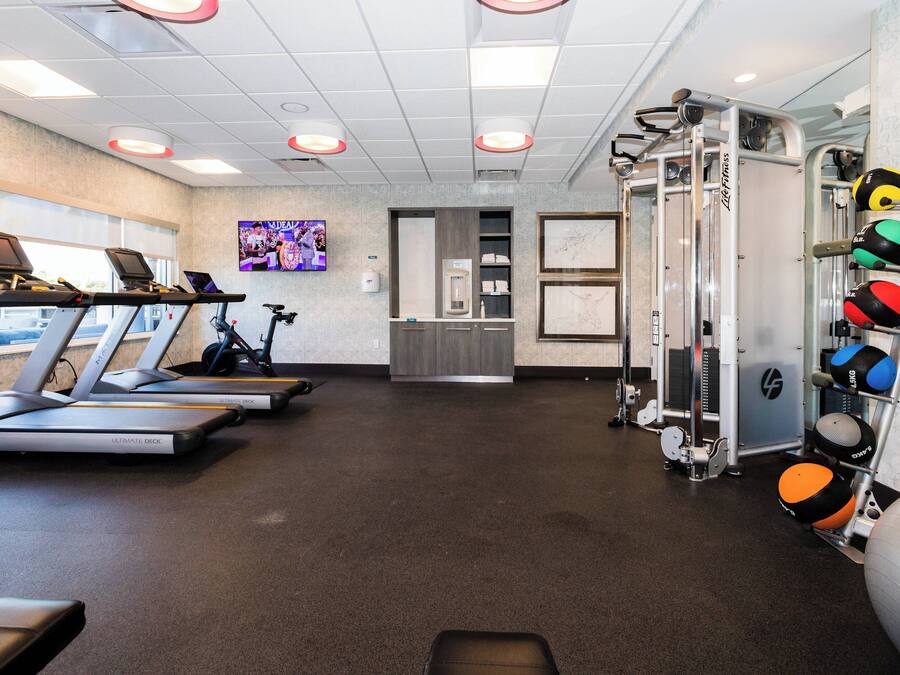 A gym with treadmills, a weight machine, and exercise balls.
