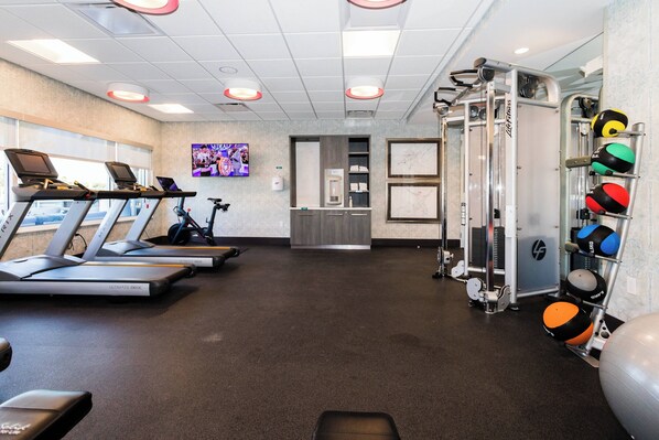Un gimnasio con cintas de correr, máquinas de pesas y pelotas de ejercicio.