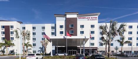 A hotel with a modern design, featuring a prominent entrance with a covered area and multiple flags.