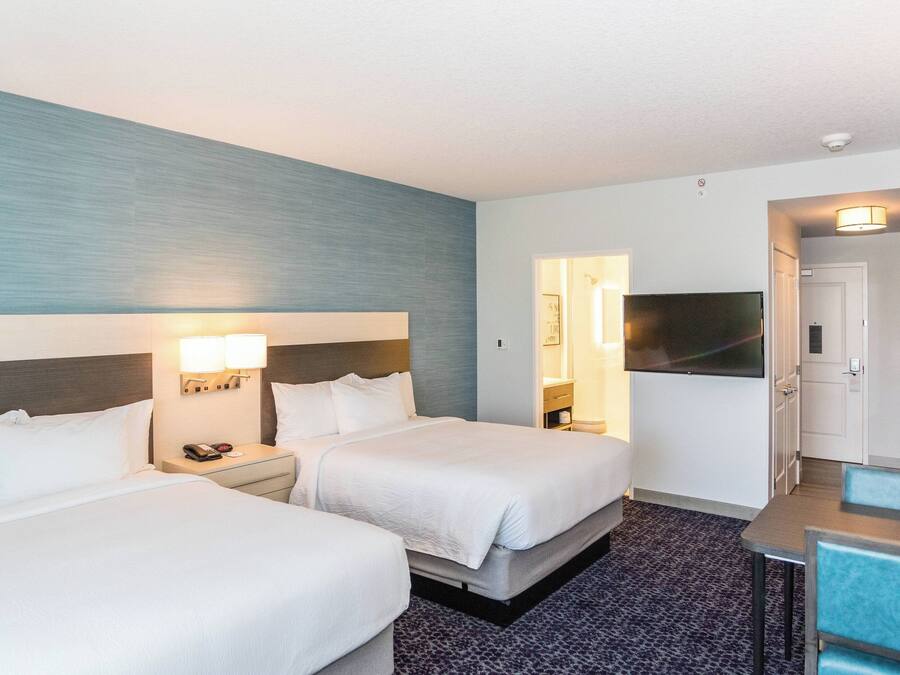 Een hotelkamer met twee bedden, een bureau, een televisie en een kitchenette.