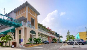 Um hotel com estrutura em dois andares, uma galeria coberta e estacionamento com carros.