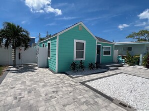 A single-story house with a green exterior and a front porch. - Ocean Breeze - Cozy Beach Cottage across from the beach. Pet friendly! (Madeira Beach)