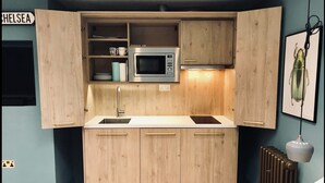 Une cuisine compacte avec des meubles en bois, un four à micro-ondes encastré et un évier.