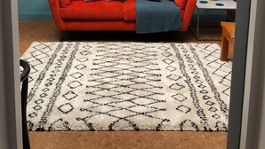 Une pièce avec un canapé rouge, un tapis à motifs et un mur bleu.