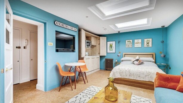 Une chambre comprenant un lit, un bureau et une kitchenette.