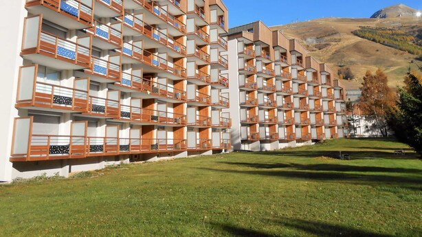 Un hotel a più piani con un design architettonico moderno, caratterizzato da balconi con ringhiere in legno e un tetto piatto.