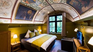 A room with a large bed, a TV, and a window with a view of trees. - Vacation in the Harz Mountains the special *****Holiday apartments Burgkaiser im Zwinger Goslar (Goslar)