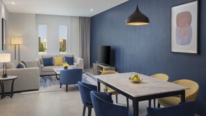 A modern living room with a sofa, chairs, a dining table, and a TV.