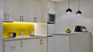 A modern kitchen with white cabinets, a microwave, and a coffee machine.