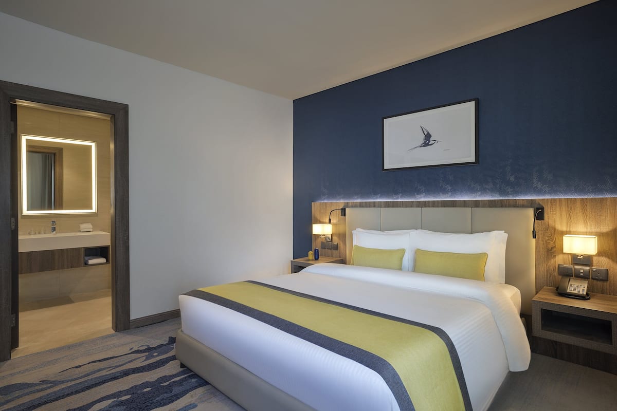 A hotel room with a large bed, bedside tables with lamps, a mirror, and a framed picture on the wall.