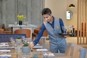 A waiter serving a table with multiple wine glasses and a centerpiece. - voco Al Khobar by IHG (Al Khobar)