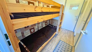 Un lit superposé avec une literie à motifs, une échelle en bois et un tapis à motifs posé sur un plancher en bois.