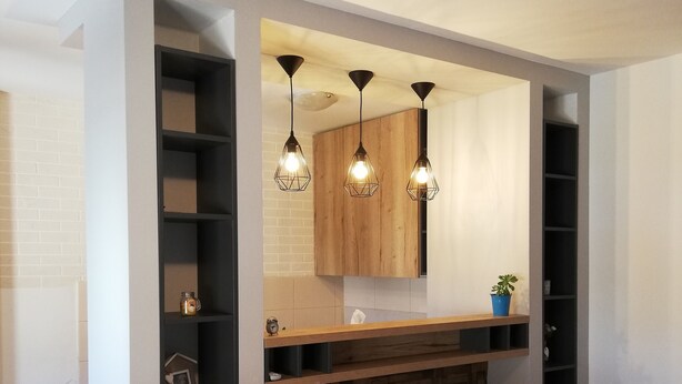 A modern living room with a built-in TV, wooden shelves, and pendant lights.